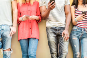 social media influencers standing in a line looking down at their phones | RM Warner Inernet Law Firm