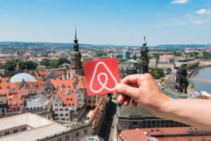 Logo Airbnb and the city on the background. | RM Warner Internet Law Firm | Fake reviews on Airbnb | Daniel Warner | Raees Mohamed