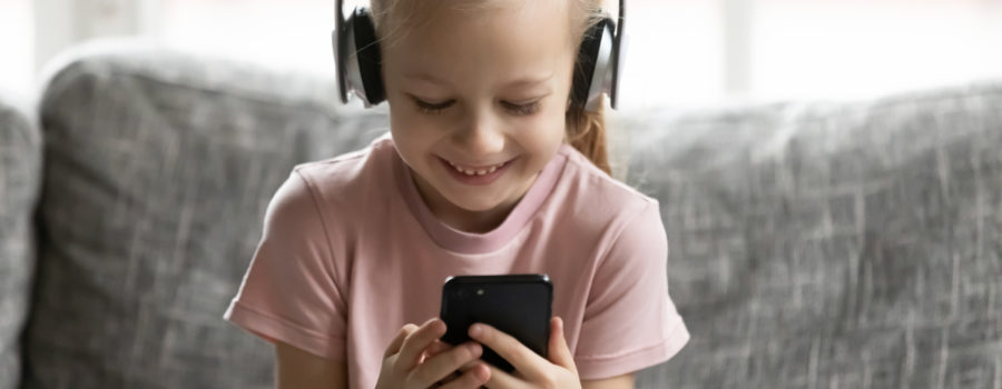 girl with headphones on sitting on couch holding iphone and watching youtube vidoes for YouTube FTC news | RM Warner internet Law Firm