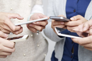 girls standing in a circle looking at social media on their phones | RM Warner Inernet Law Firm
