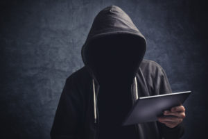 anonymous man in black hoodie holding ipad | RM Warner Inernet Law Firm