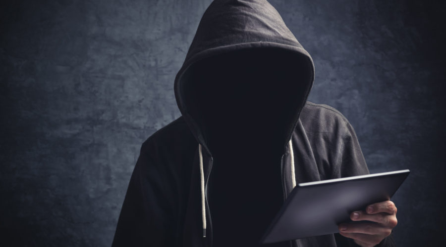 anonymous man in black hoodie holding ipad | RM Warner Inernet Law Firm