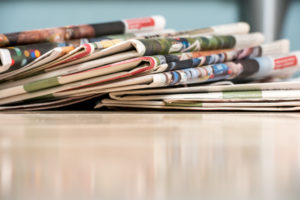 newspapers in a stack on wood counter | RM Warner Inernet Law Firm