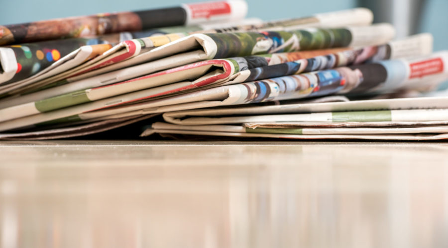 newspapers in a stack on wood counter | RM Warner Inernet Law Firm