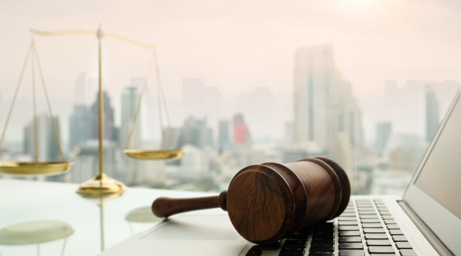 gavel sitting on laptop with weights of justice in the background | RM Warner Inernet Law Firm