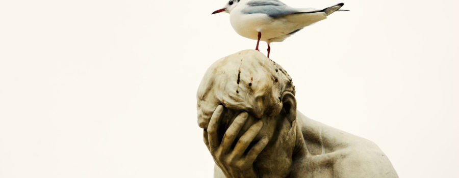 statue of a man with face in hand with bird sitting on top of his head | RM Warner Inernet Law Firm