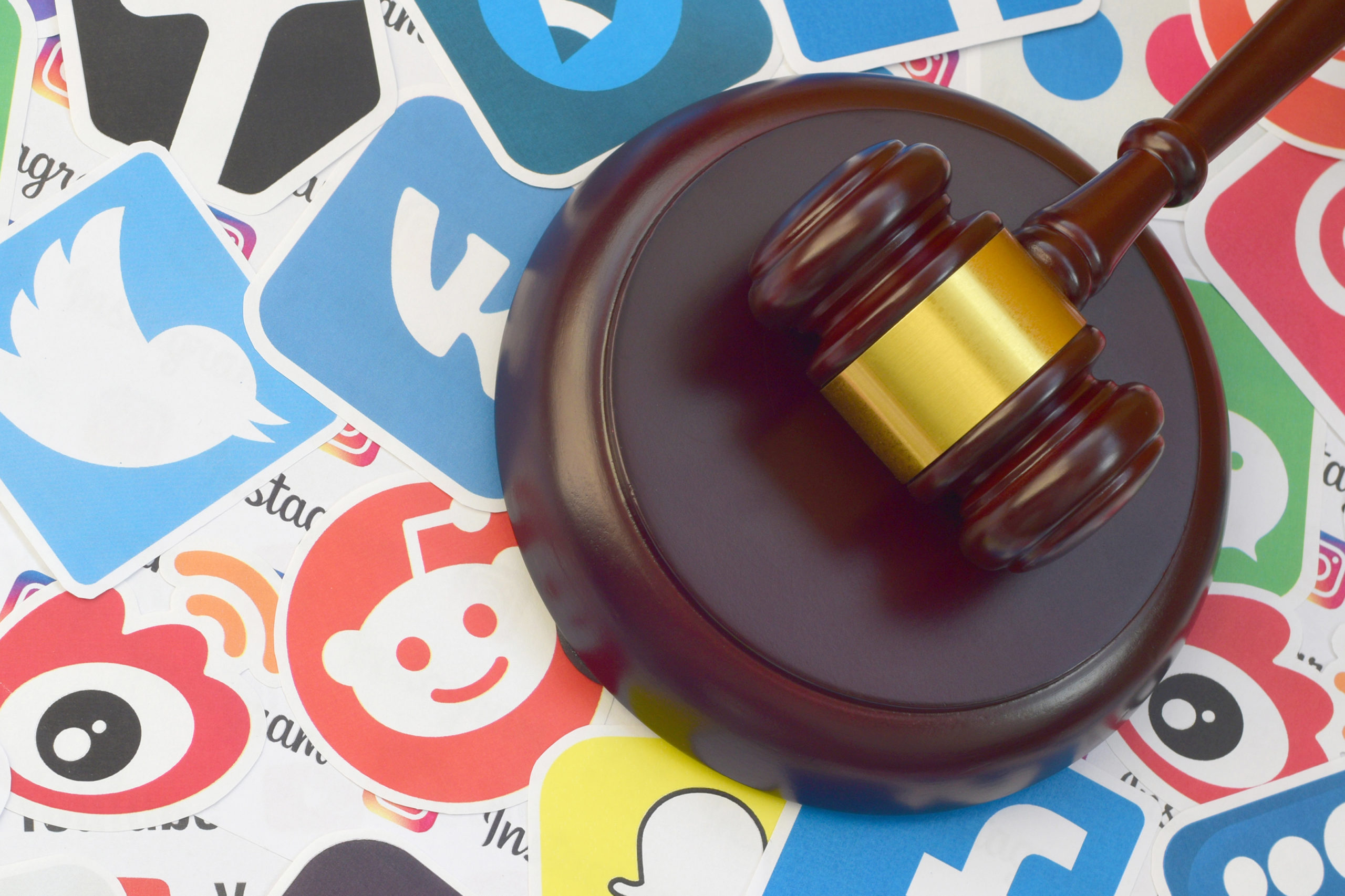 wooden gavel surrounded by social media stickers | Will TikTok be Banned in the US? | RM Warner Internet Law Firm | Daniel Warner | Daniel R. Warner | Raees Mohamed